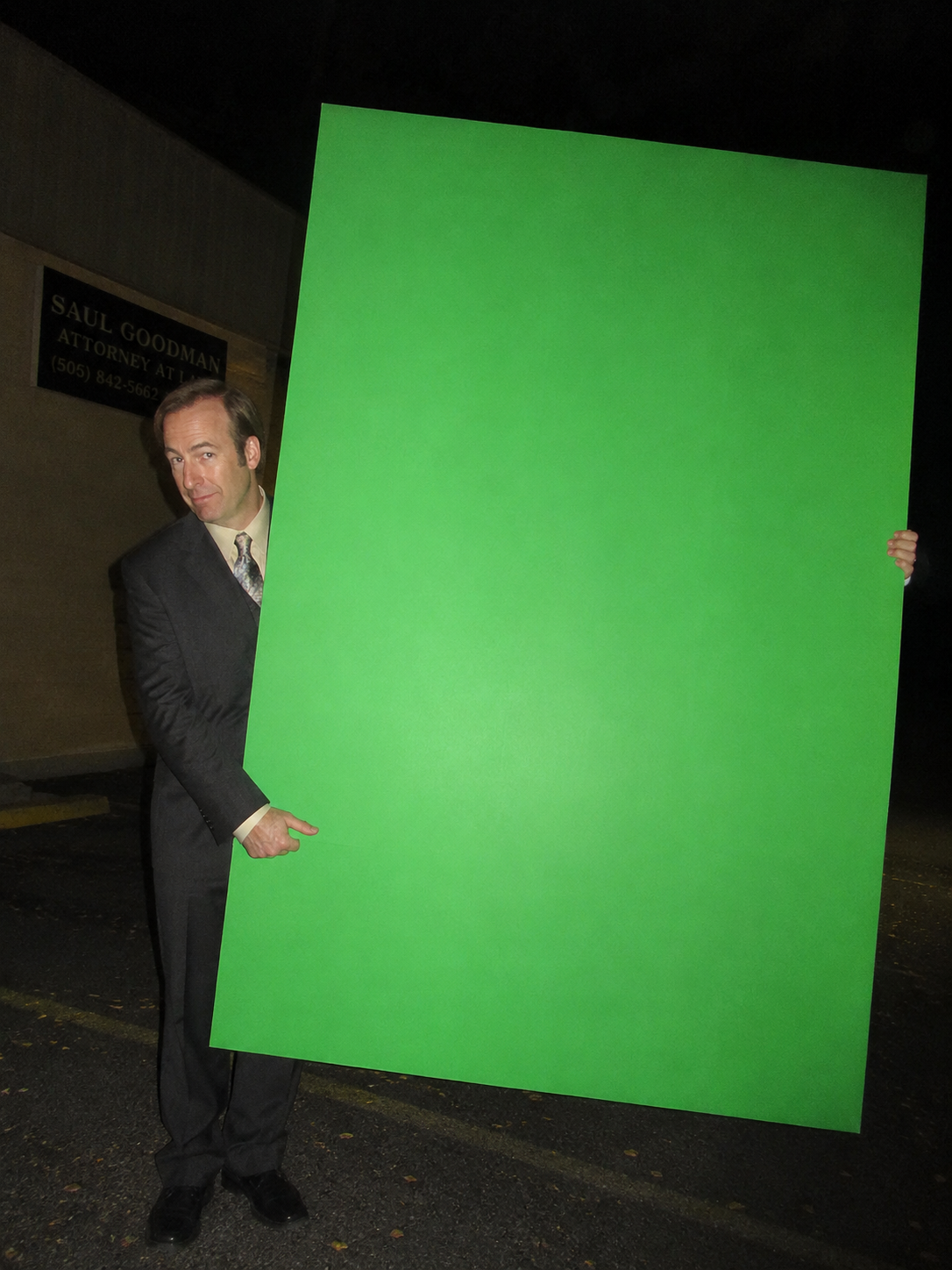 A funny flash-photo portrait of a lawyer holding a large green board